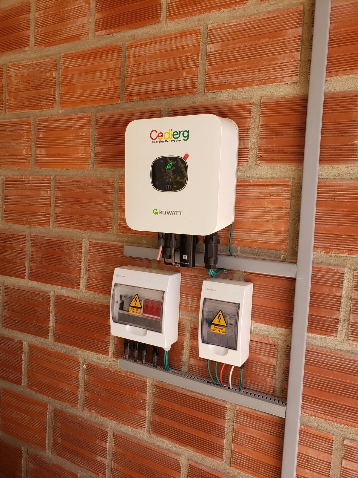 Inversor y tableros de protección instalados por CEDIERG en pared de ladrillo